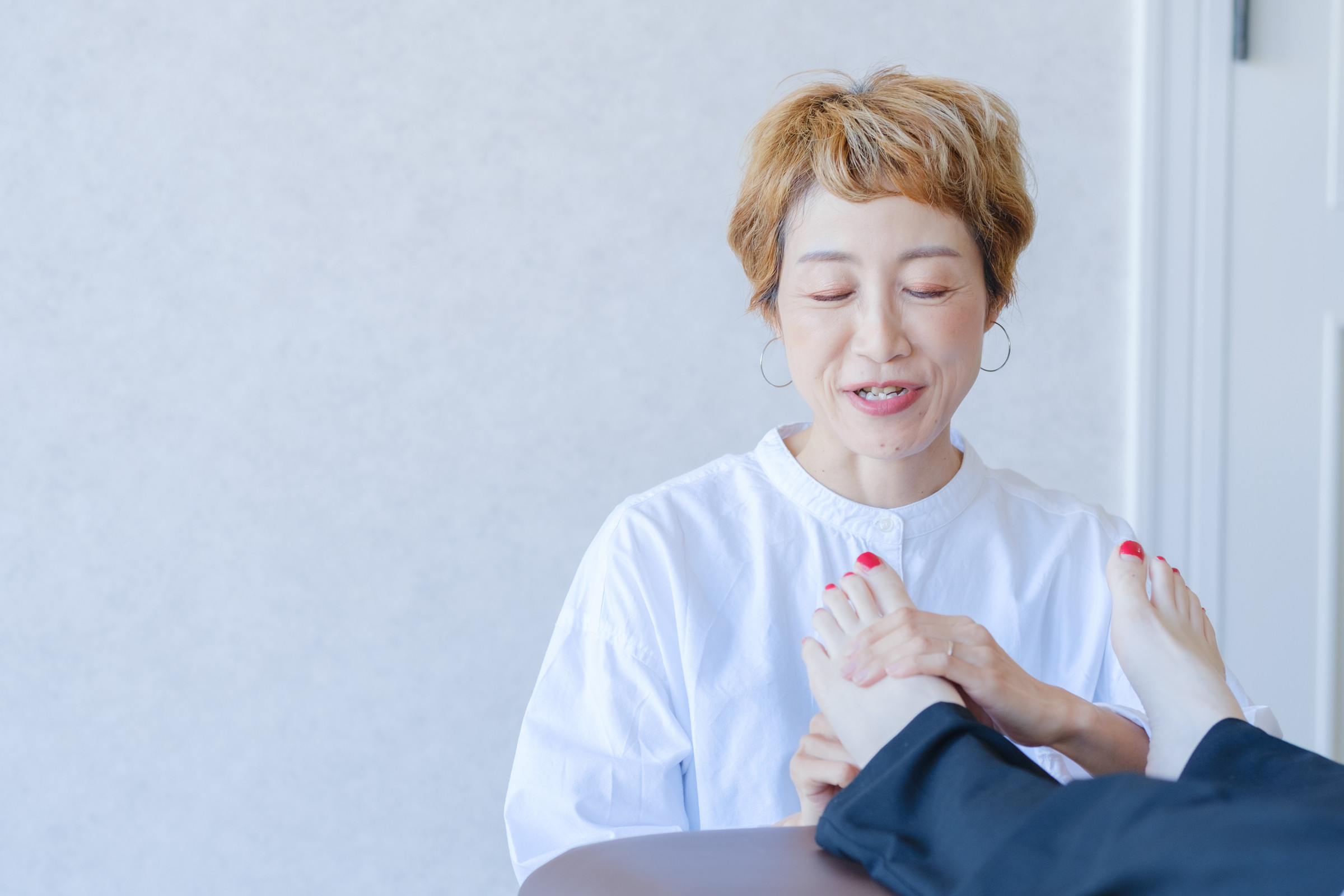 施術中、相手の足に両手を添えて表情をゆるめるよりこ